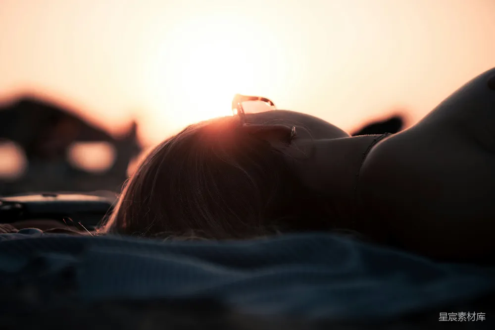 海滩上一个女子躺在沙滩上靠近海边