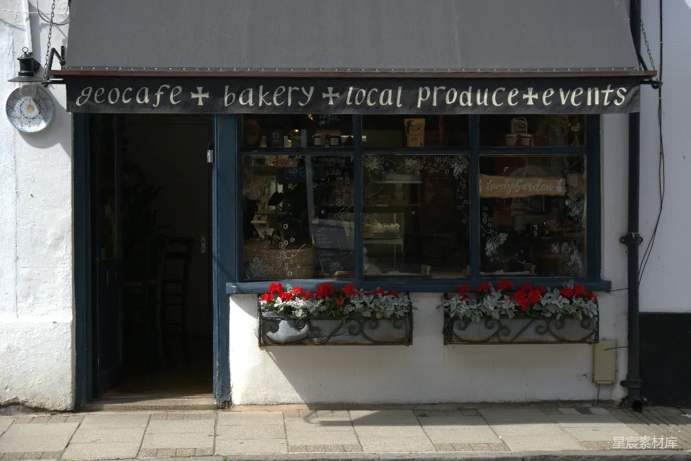 一家充满温馨的生态咖啡馆和 Bakery 店面，周围摆满了鲜艳的花箱。