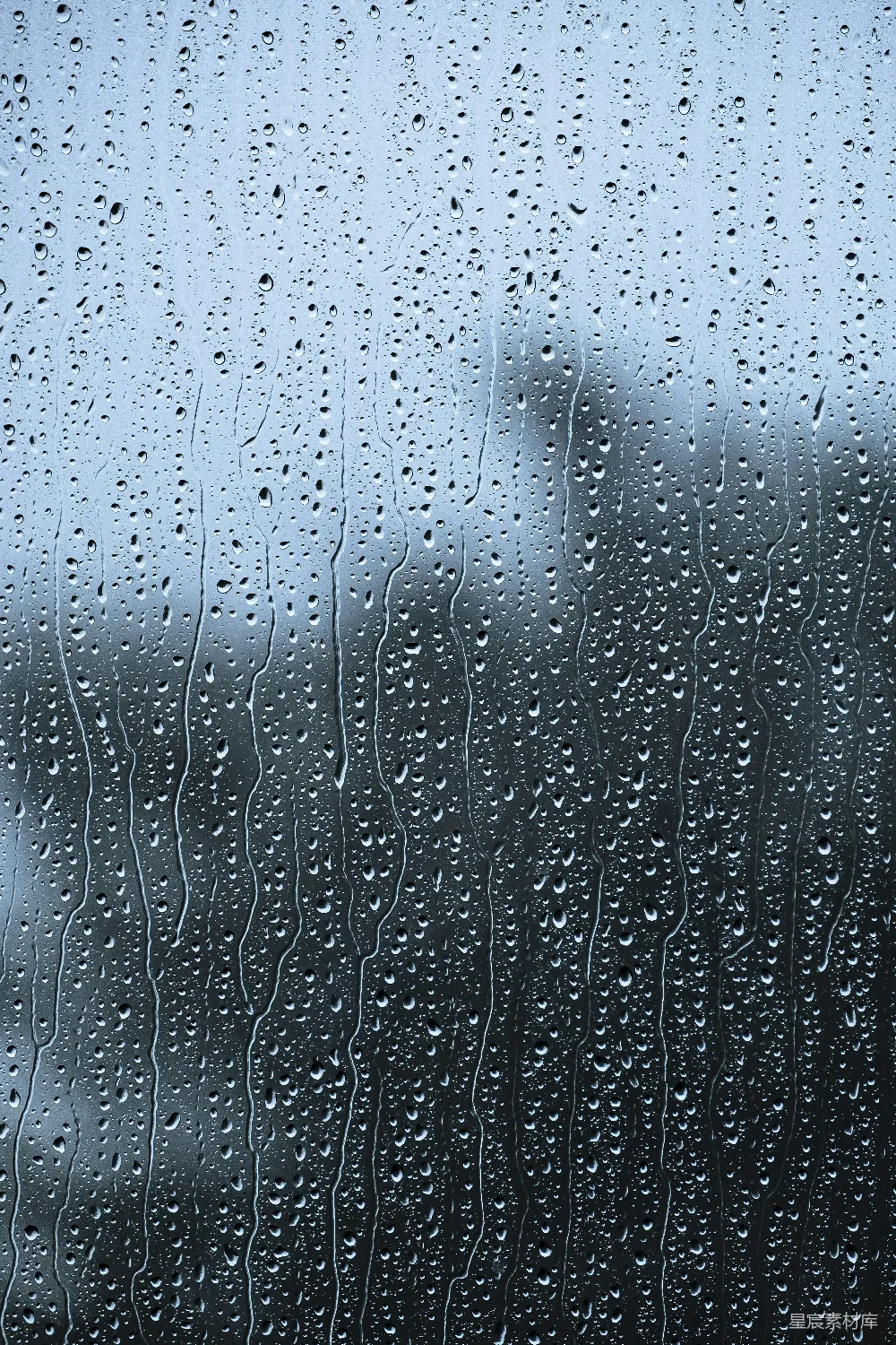 高清摄影  雨滴落在窗户上，背景中有一座建筑物。