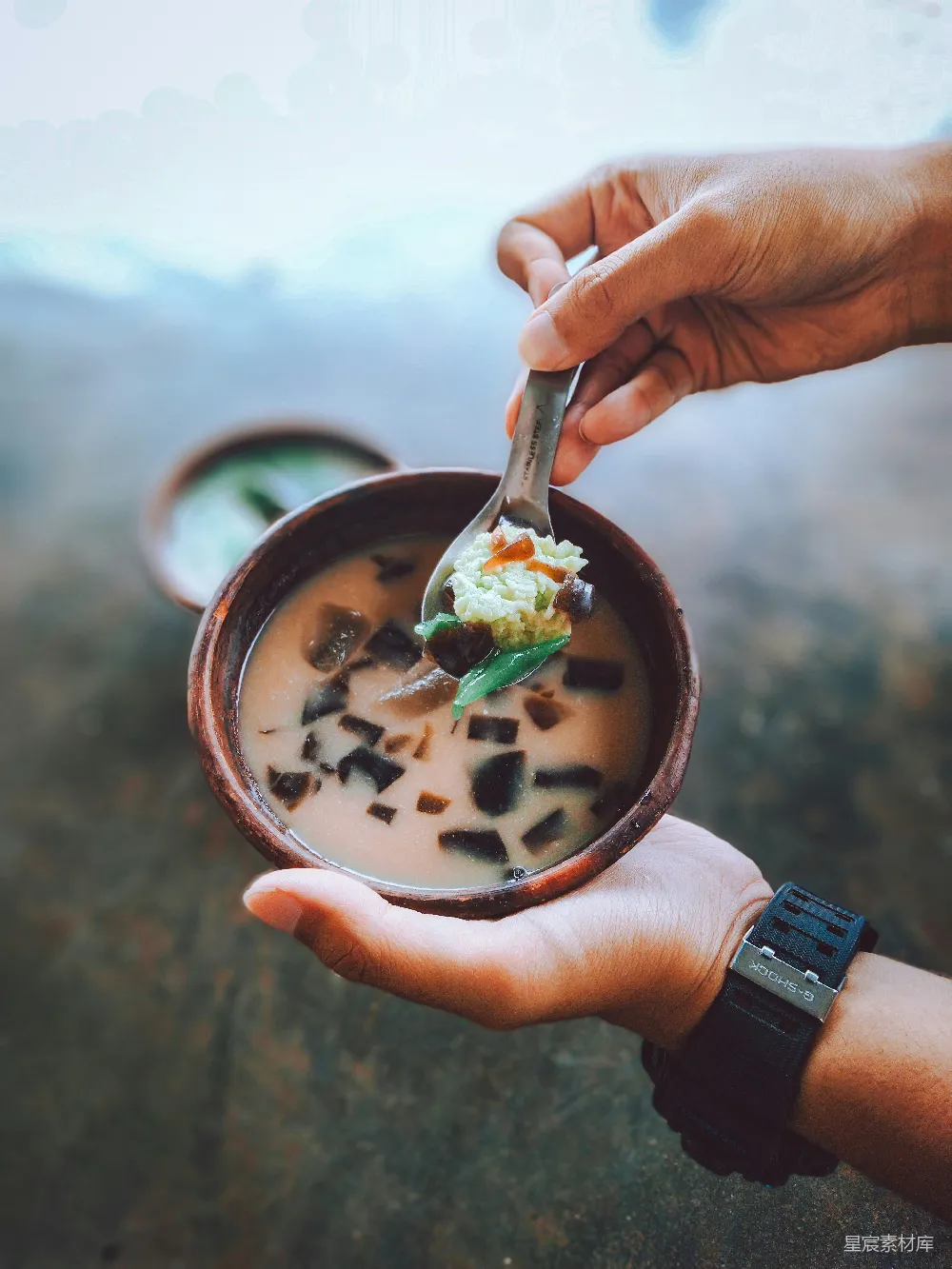 手持一碗食物的人，手里拿着勺子。