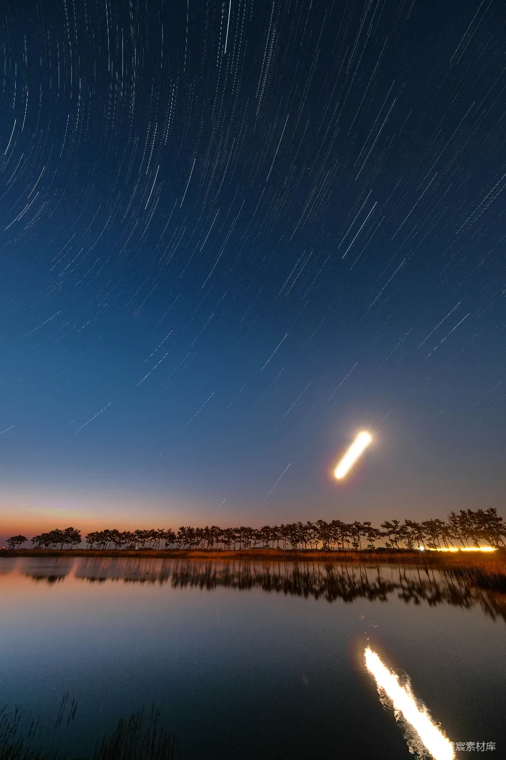 夜幕下湖泊旁的星空轨迹