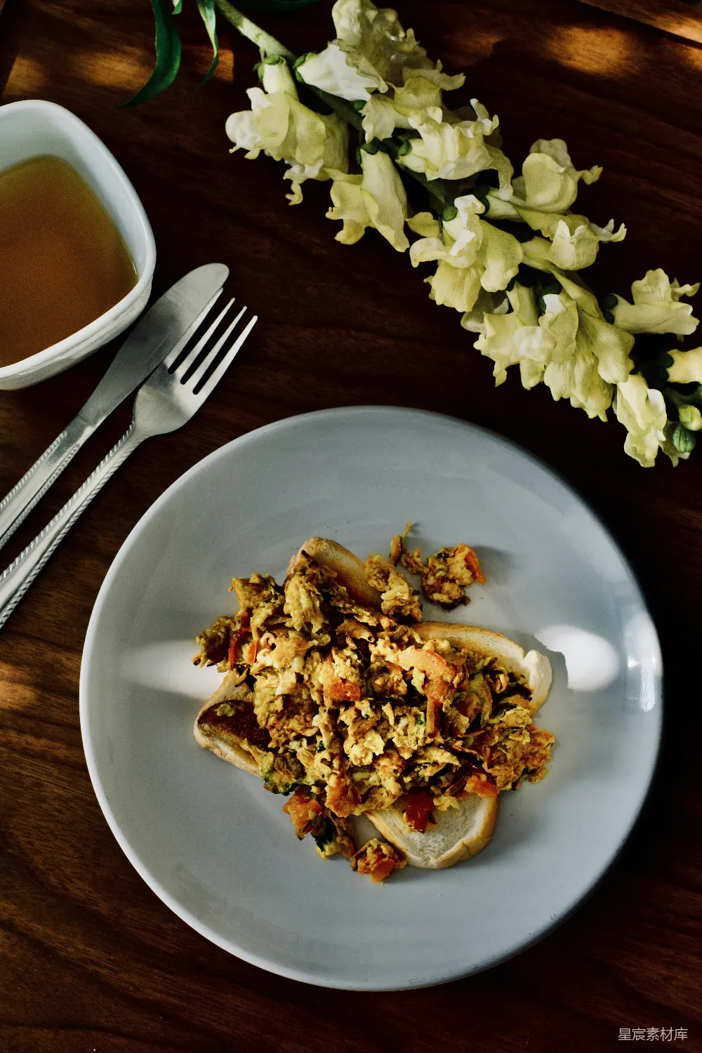 一个白盘子上面放着食物，旁边有一杯茶。