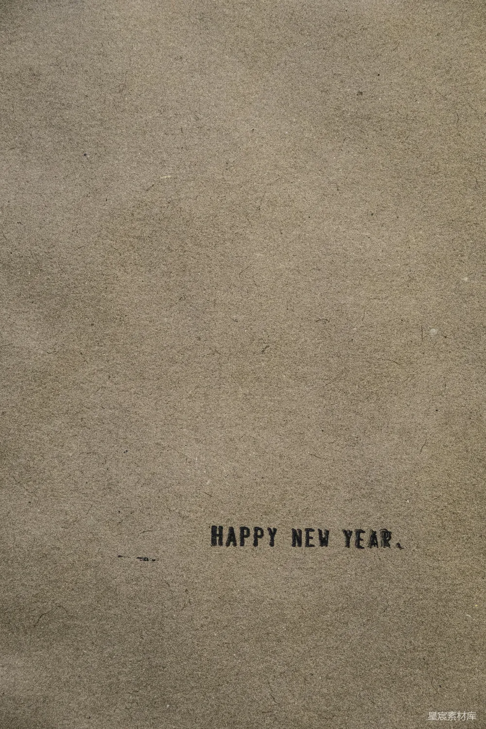 高清摄影  一张棕色的纸上写着“新年快乐”的字样。
