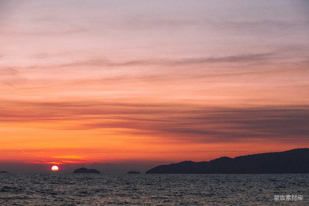 夕阳映照在一片水面上，背景是连绵的山峦。