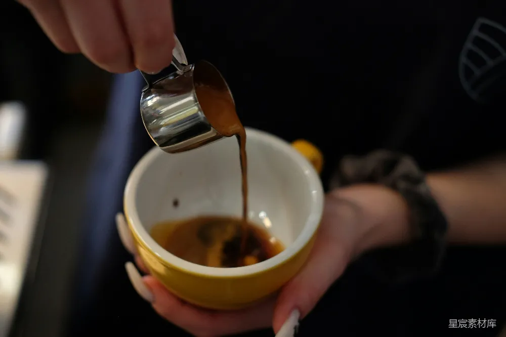 一个人将咖啡倒入一个黄色的杯子里。