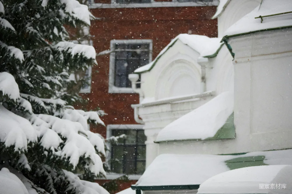 红色的消防栓覆盖着白雪，位于一幢红砖建筑前