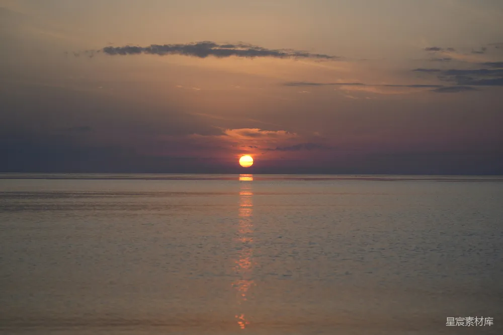 一湾平静的海水中美丽的日落与太阳倒影。