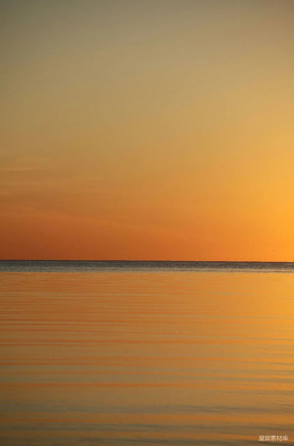 夕阳下的橙色天空中平静的海面