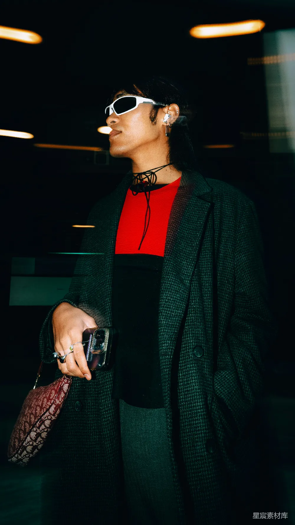 一个穿着黑色大衣和戴着太阳镜的女人拿着手提包。
