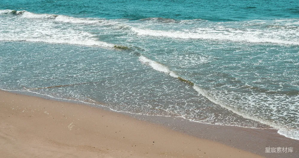 白天棕色海滩岸边有蓝色的洋流波浪。