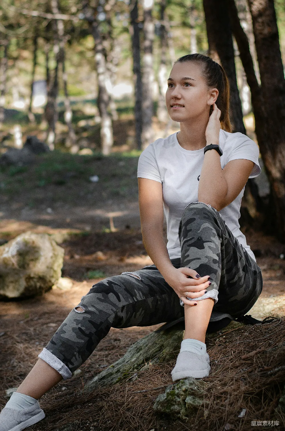 白色长袖圆领T恤着装者与黑色裤子的女士在白天坐在棕色岩石上静坐