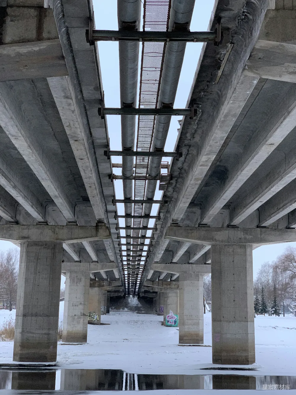 高清摄影  混凝土桥梁和管道横跨在雪后的冬季景观之上。