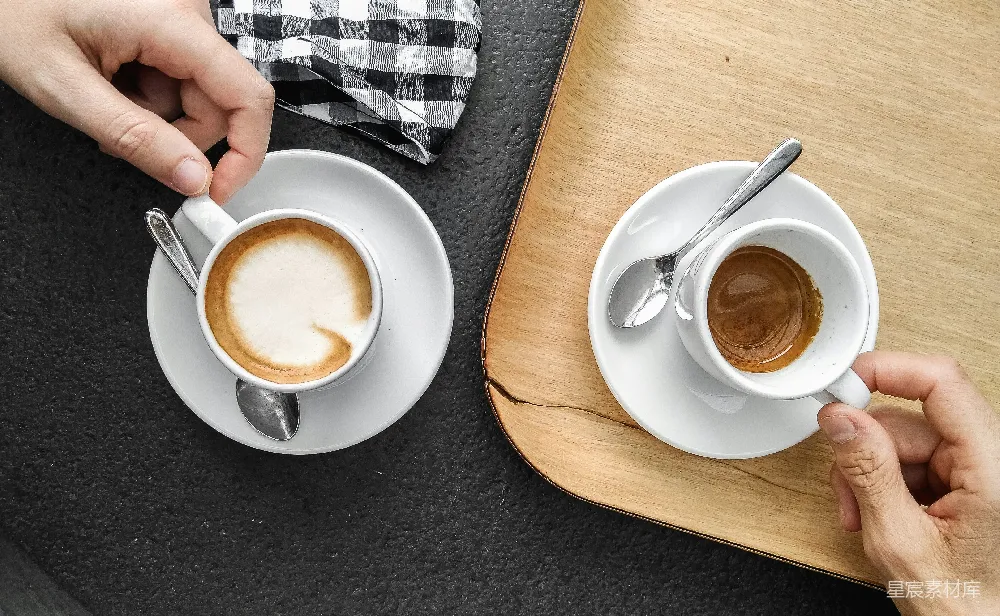 手持白色陶瓷杯的人手中握着一杯棕色液体
