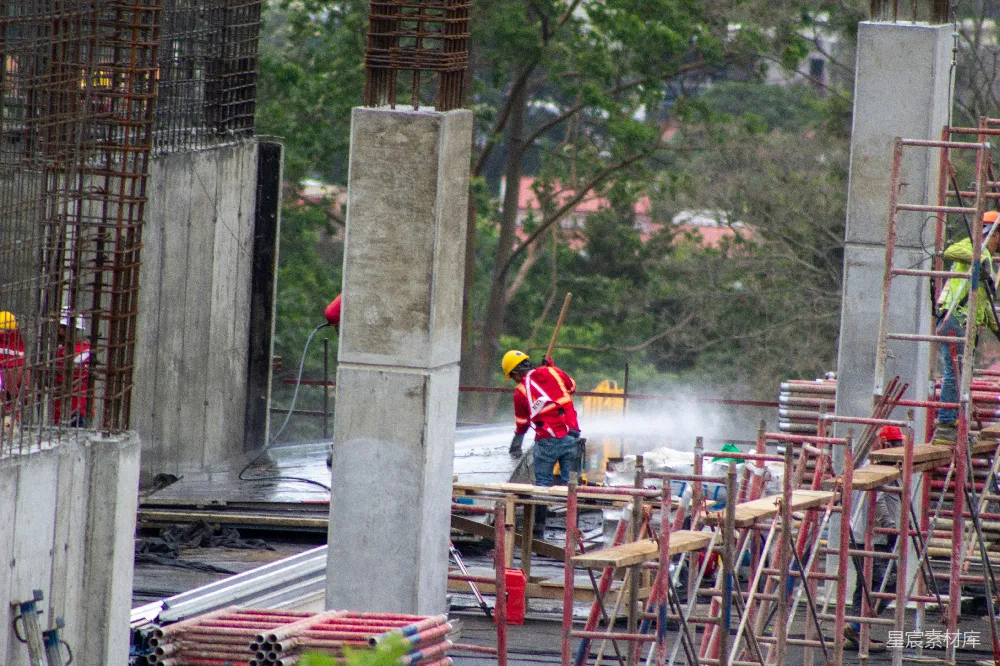 高清摄影  工人们在混凝土建筑施工工地喷水。
