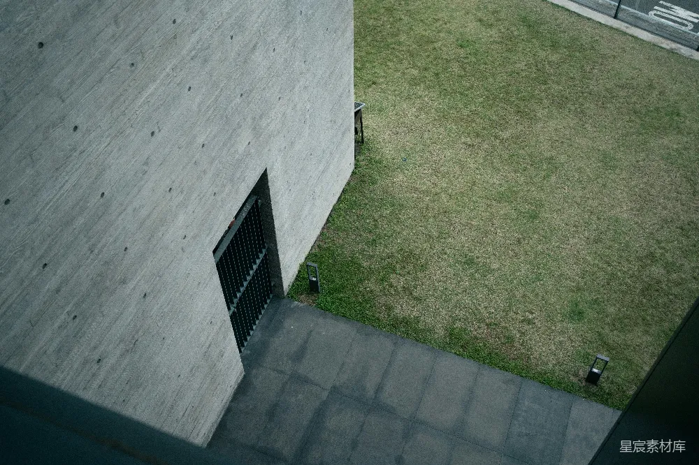 高清摄影  混凝土建筑外墙，庭院中长着草地，路径蜿蜒其中。