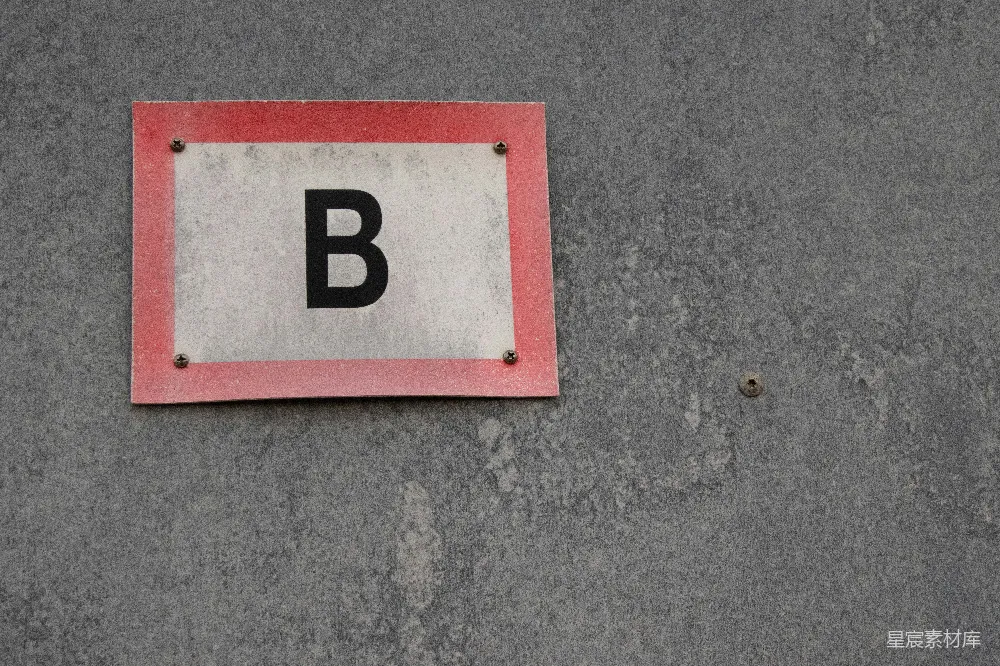 高清摄影  灰色墙上有红色边框的标志，上面有一个黑色的“b”。