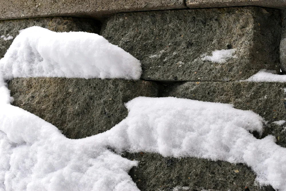高清摄影  一条被雪覆盖的石墙靠近人行道。