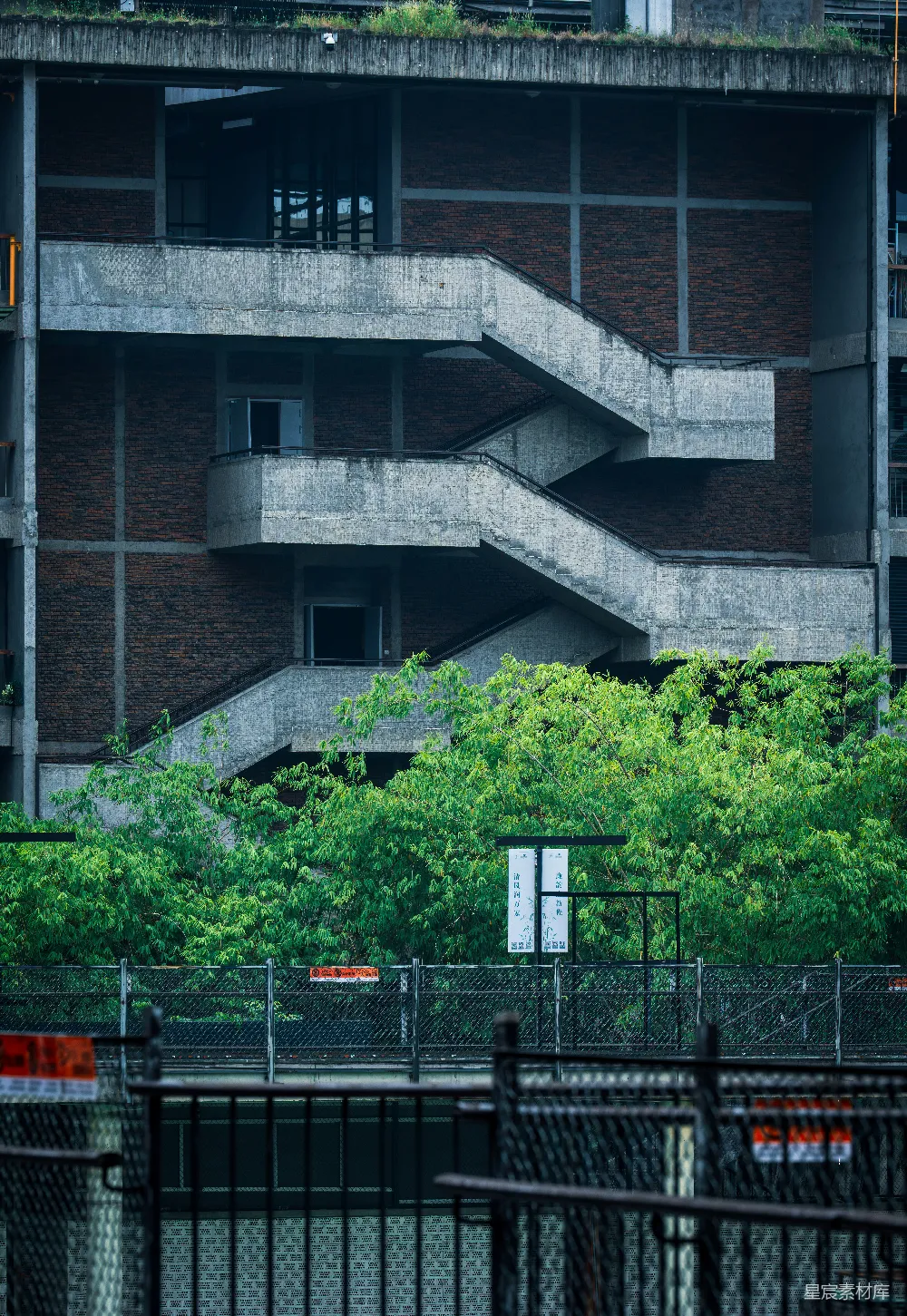 高清摄影  砖砌建筑的混凝土楼梯井，旁边有绿色的植被。