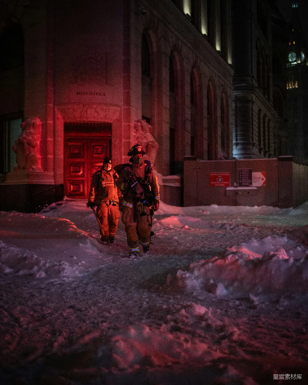 几个消防员走在覆盖着积雪的街道上