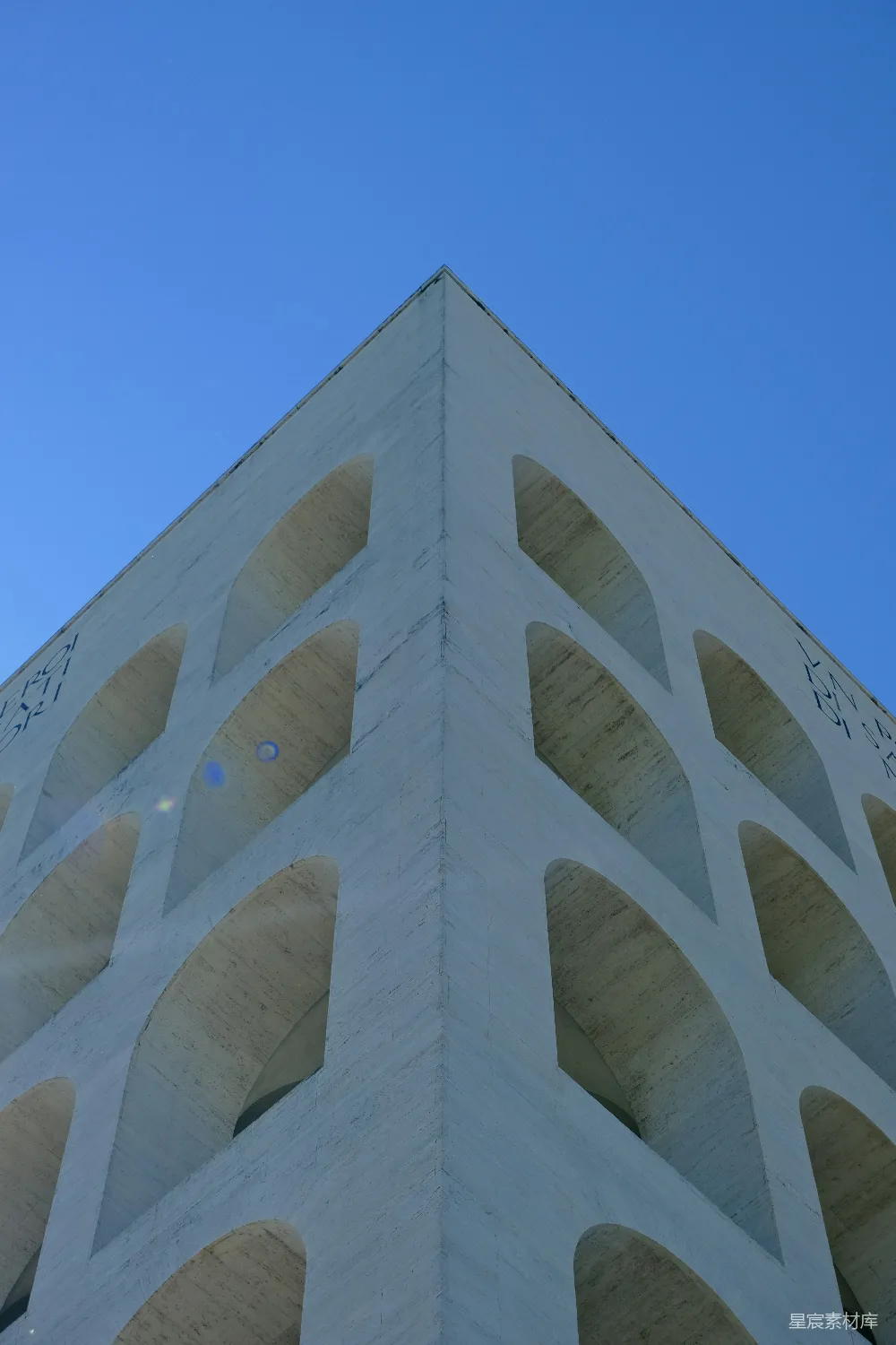 现代建筑 facade 上方有拱形窗户，背景是蔚蓝的天空。