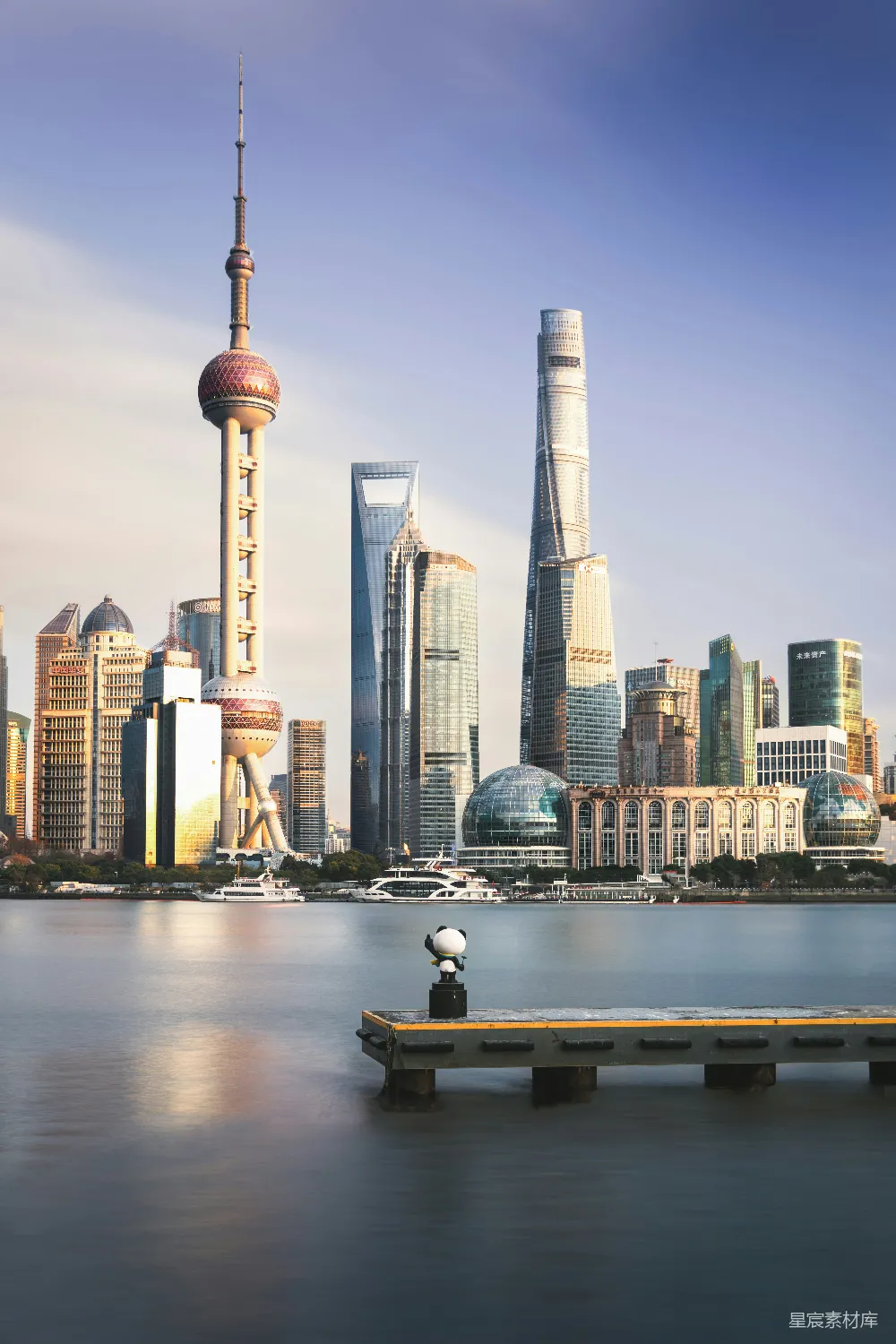 现代摩天大楼俯瞰着一条平静的河流和一个小身影。