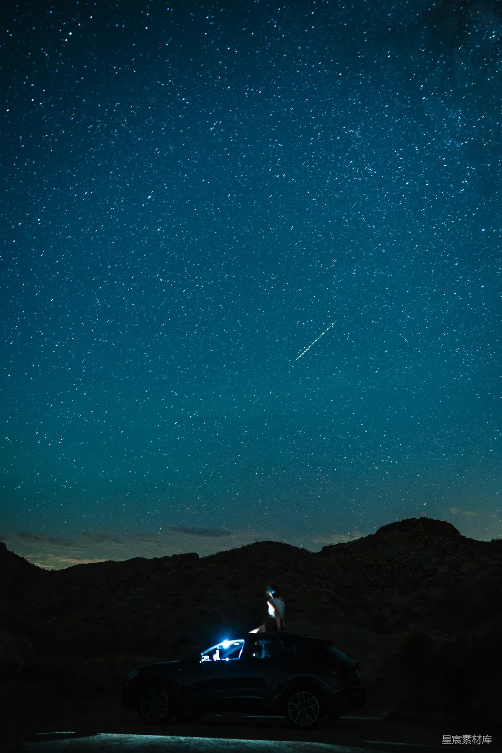 一辆车停在星光灿烂的夜空前