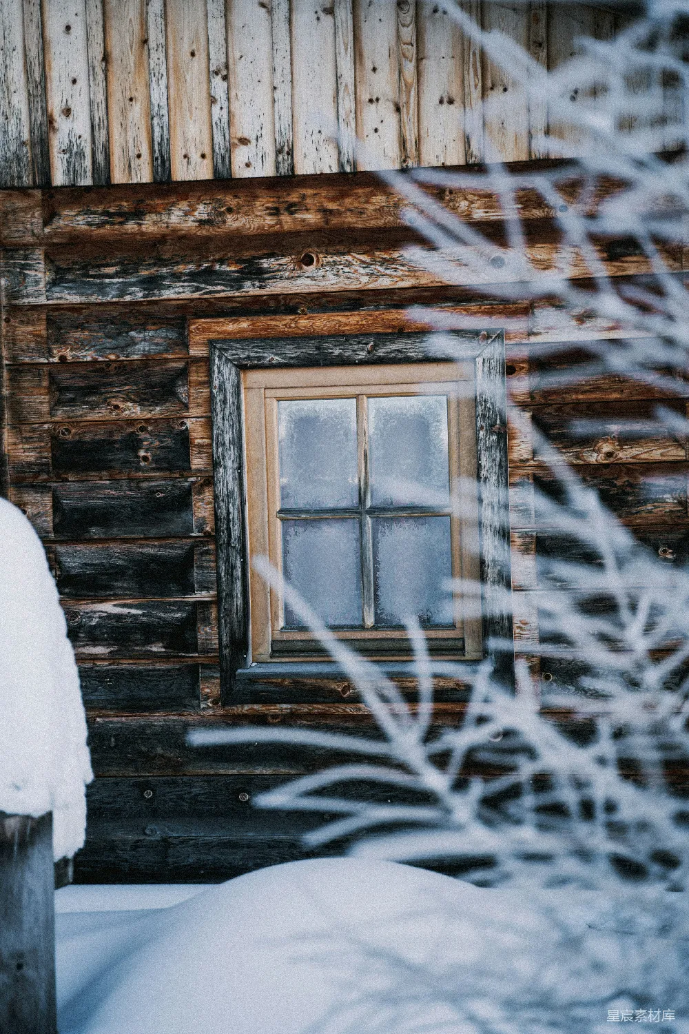 地面上覆盖着白雪的小木屋和一扇窗户