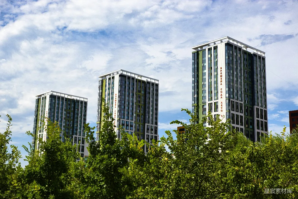 三座现代高层建筑背后有绿树。
