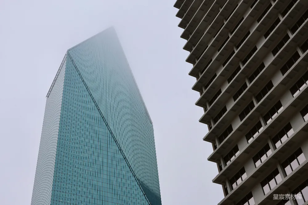 两座现代摩天大楼拔地而起，映衬在一片迷雾的天空中。
