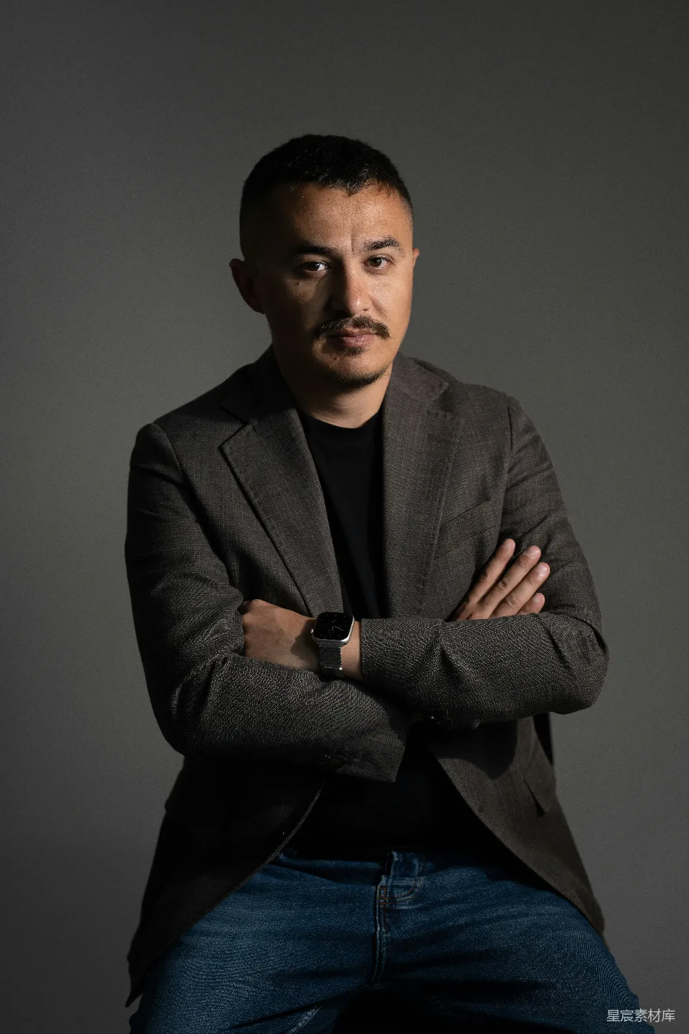 一名男子叉腰站立，穿着西装。