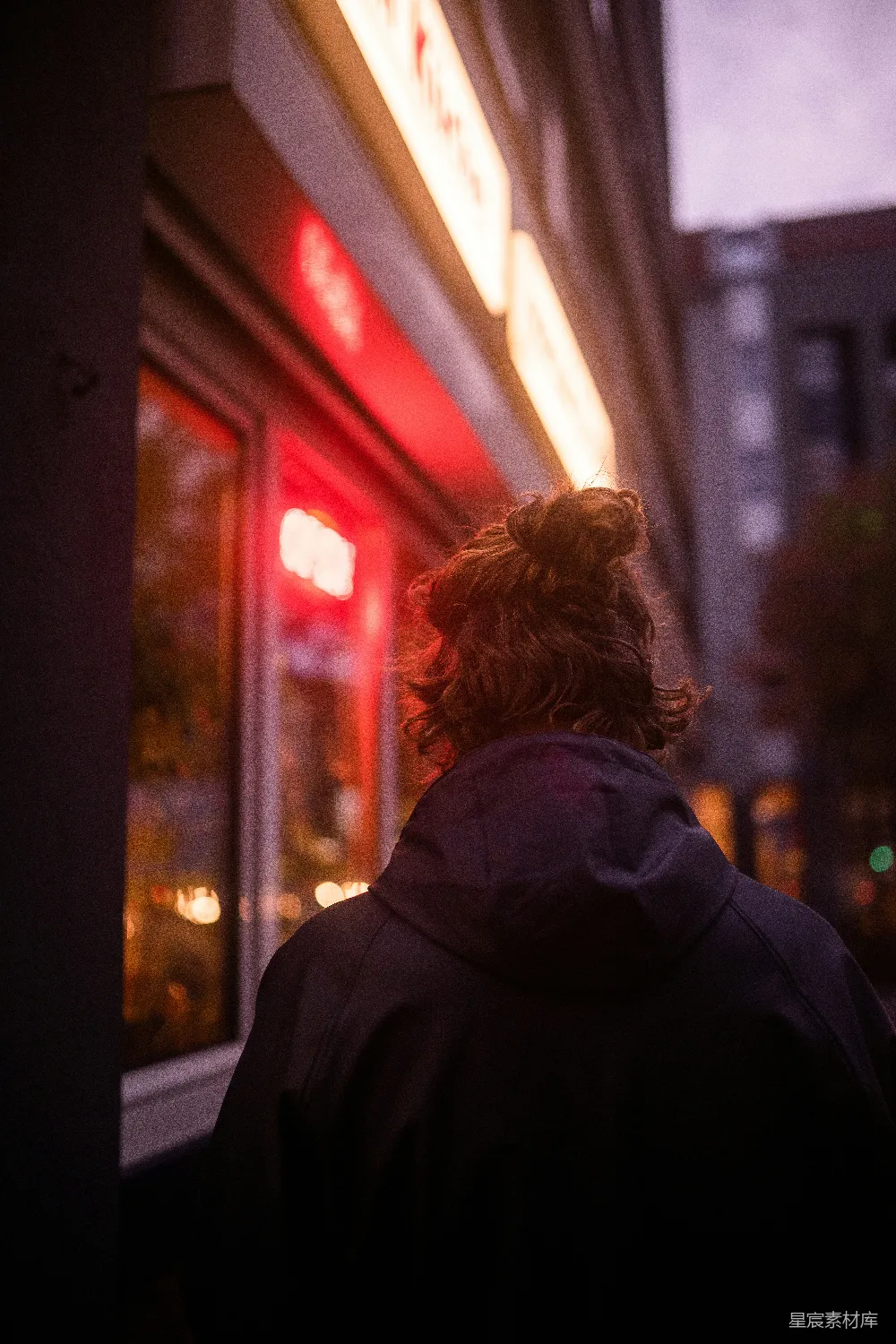 黑色风衣女站在夜晚靠近玻璃窗的地方