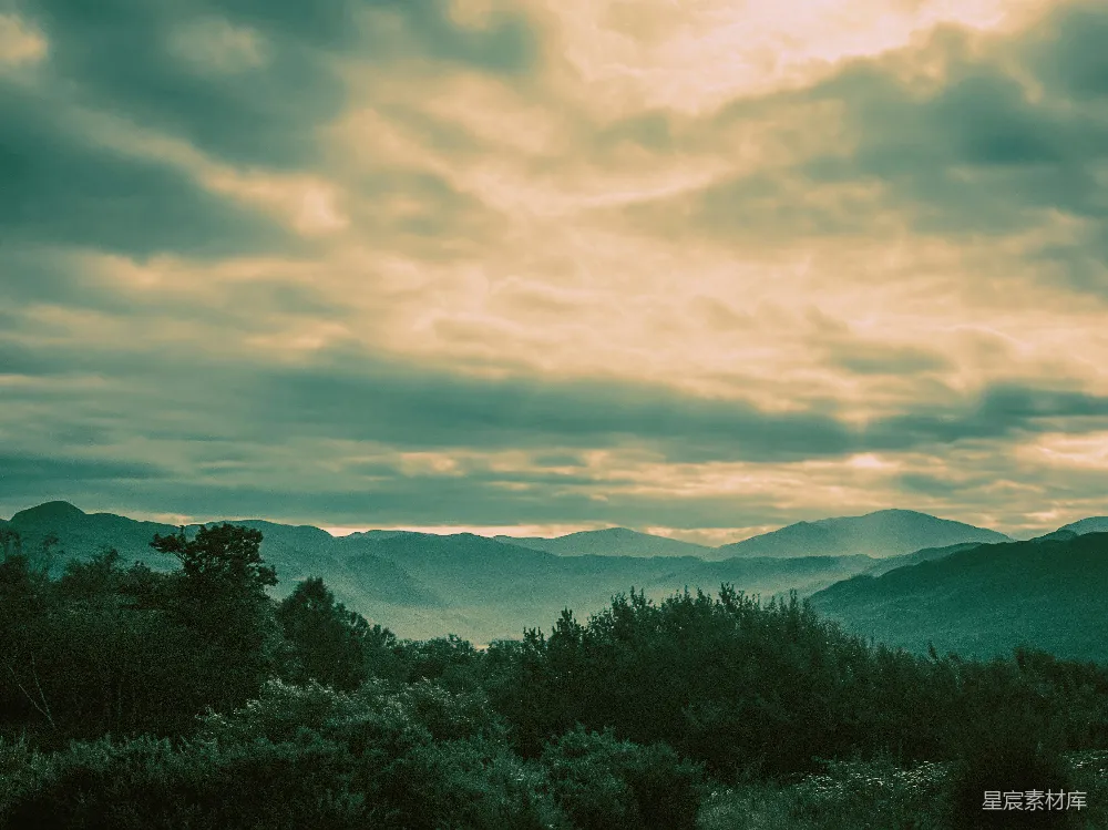 一幅山峦景色图，天空中有云。