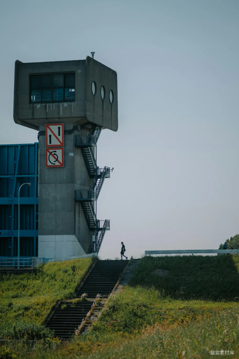 高清摄影  一个人走上一座粗犷建筑旁的混凝土楼梯。