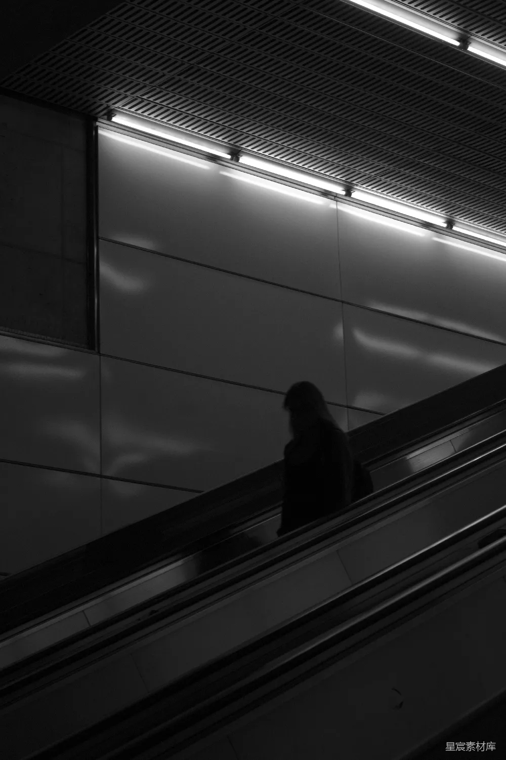 黑色外套的人站在电梯扶手上