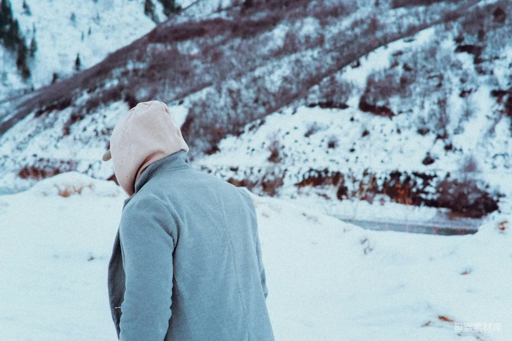 一个男人站在雪地里穿着夹克。