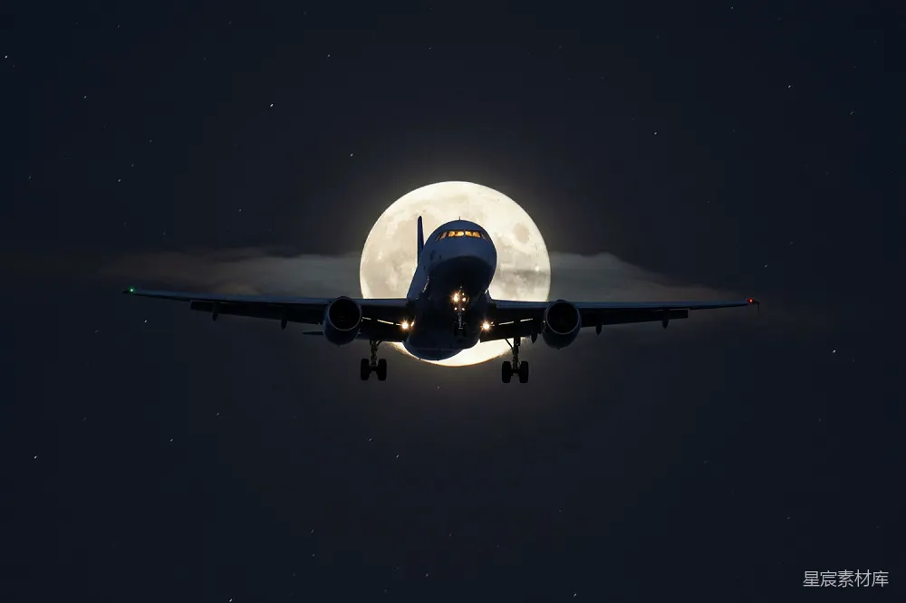 夜空中一架飞机在一轮满月的前方飞行。