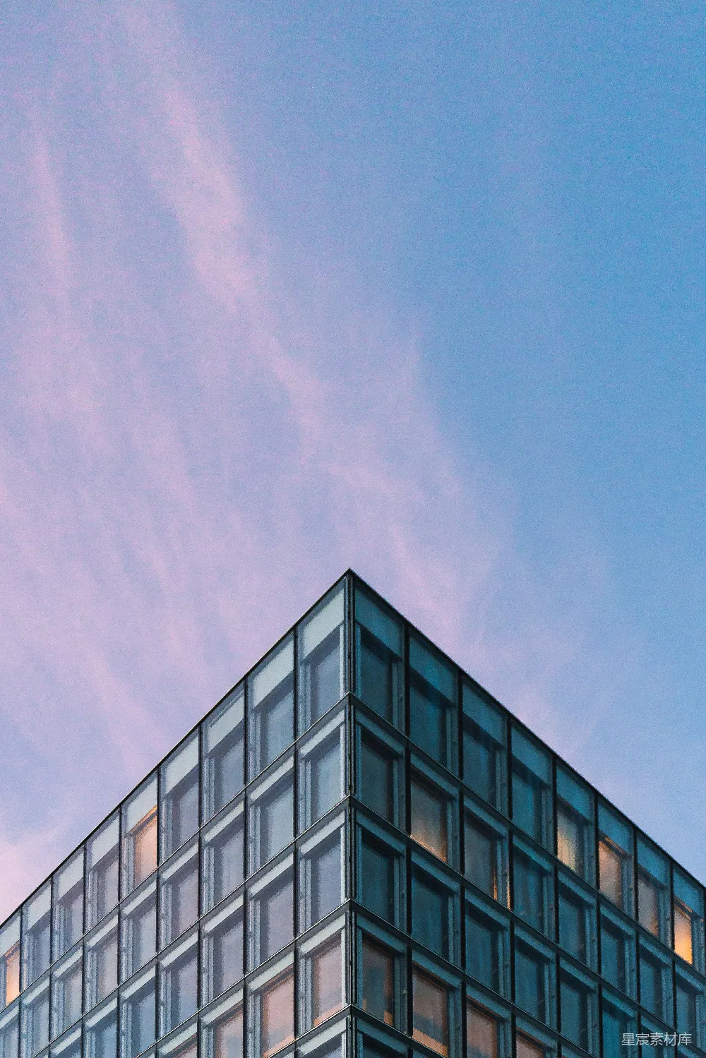 现代玻璃建筑角落映衬着粉色的天空。