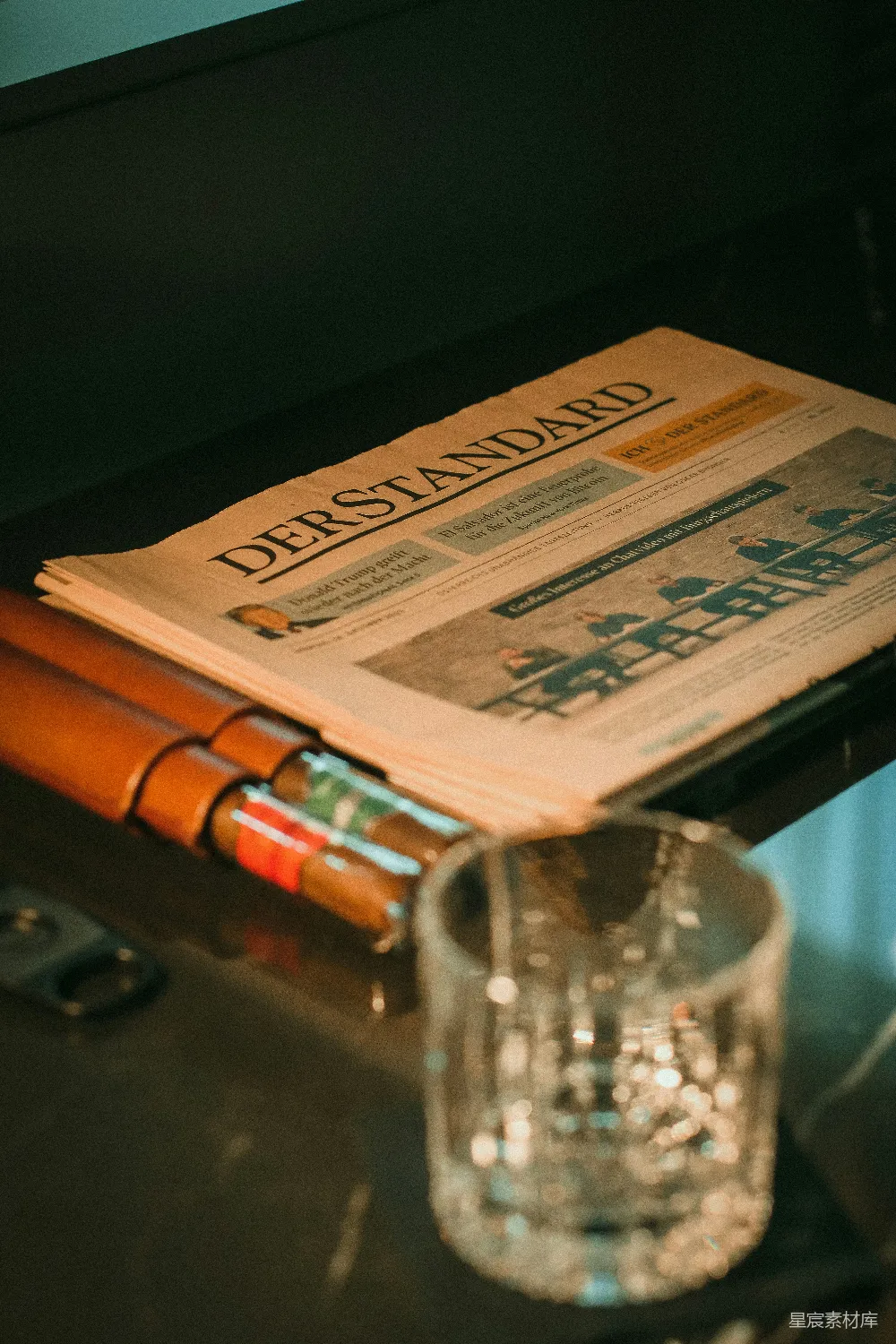 高清摄影  一份报纸放在桌子旁边的一杯玻璃杯上面。