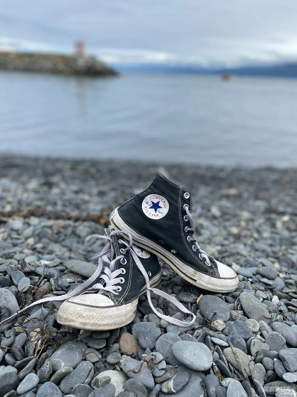 黑色匡威高领靴鞋在 rocky shore 落脚