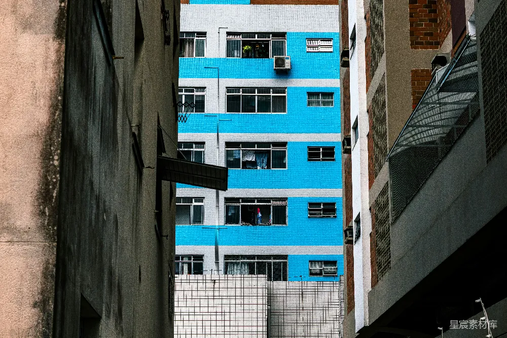 一座蓝白相间的建筑位于其他两座建筑之间。