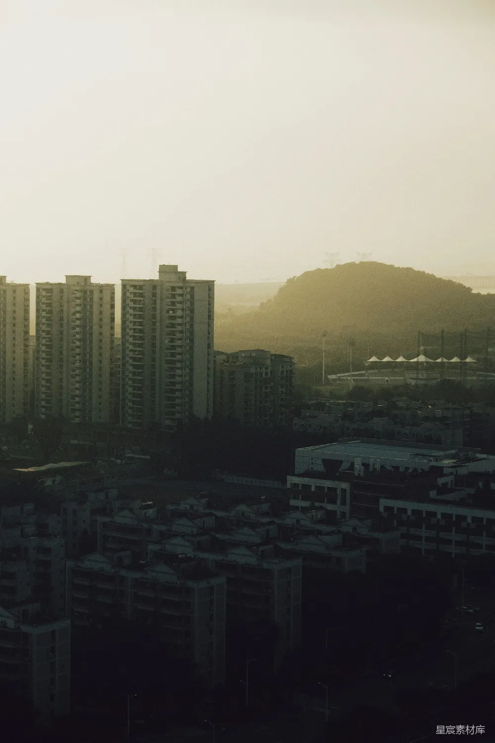 高耸的公寓建筑在日落远处的山丘上。