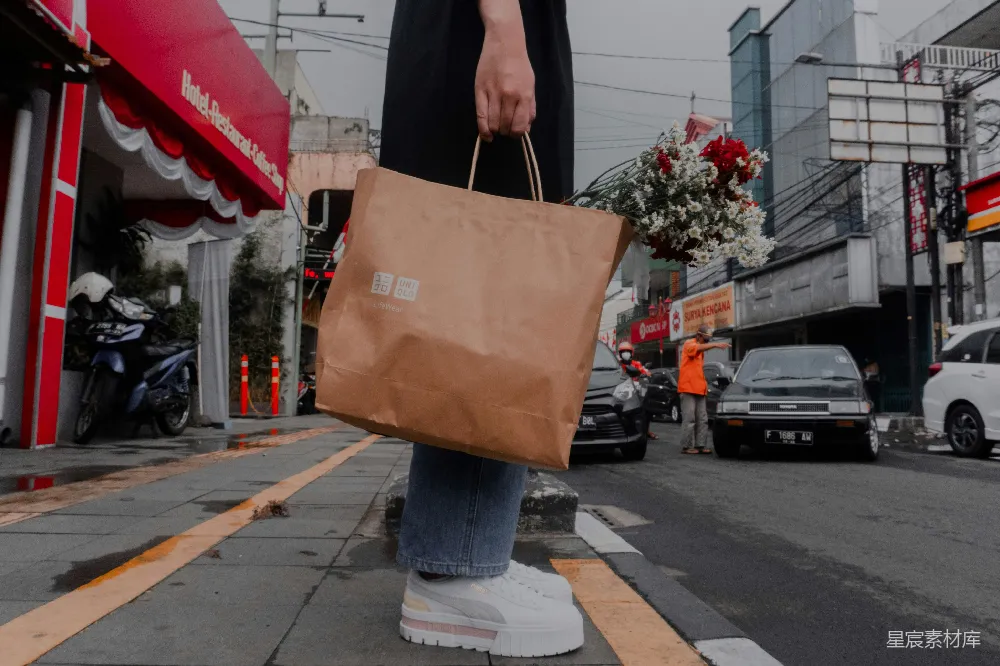 高清摄影  一个人拿着一个棕色的包走在城市街道上