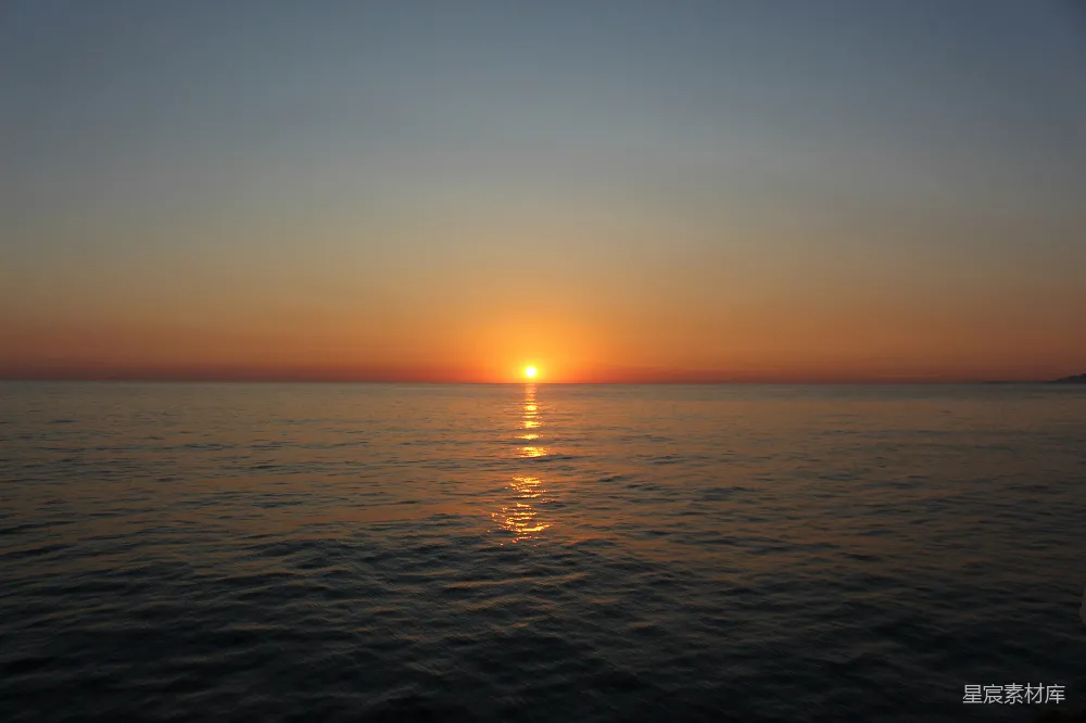 夕阳照耀在一片平静广阔的海洋上。