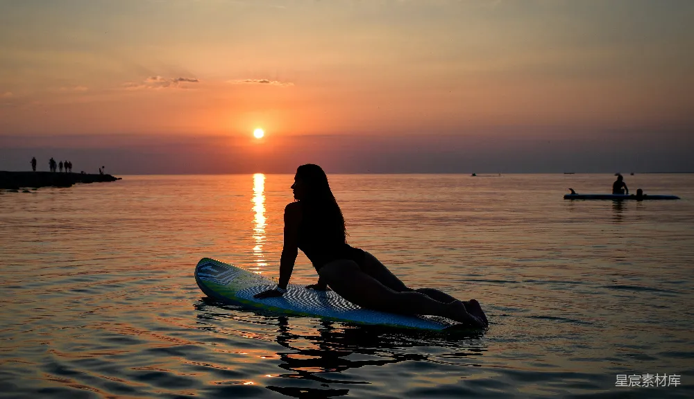 女士在日落时分于桨板上做瑜伽
