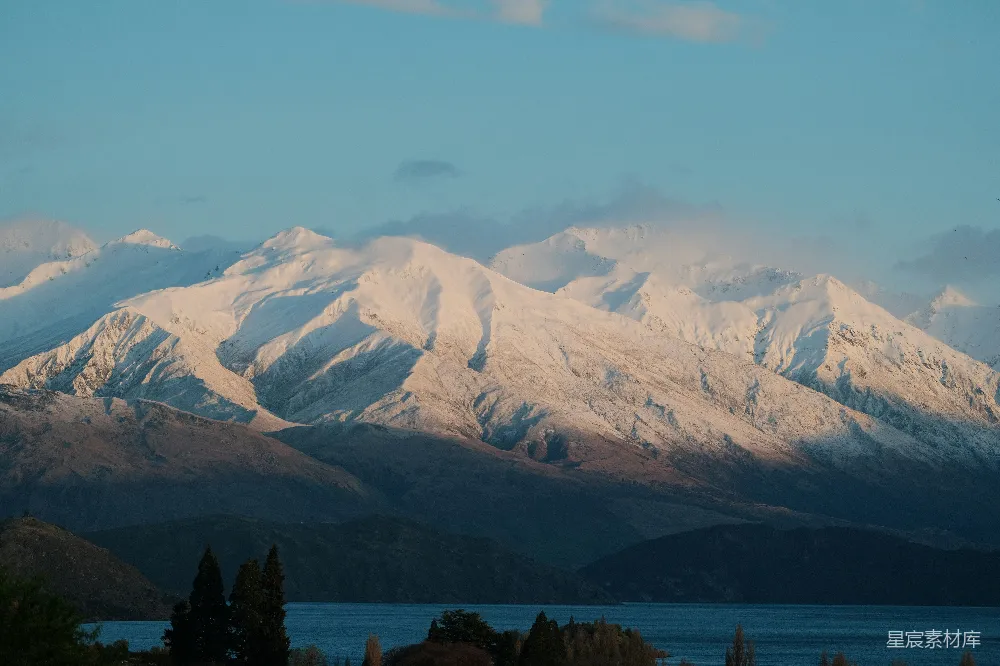 一幅覆盖着白雪的山峦远景中有一片湖泊。