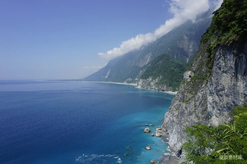 绿山蓝海间灰山白天映照蓝天之下