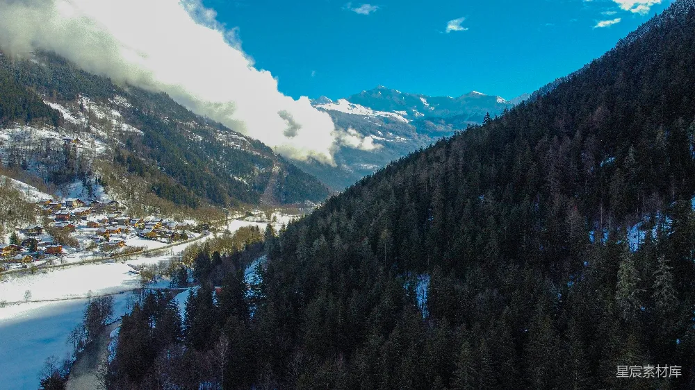 远处有一座被雪覆盖的山峦，旁边有一个小村庄。