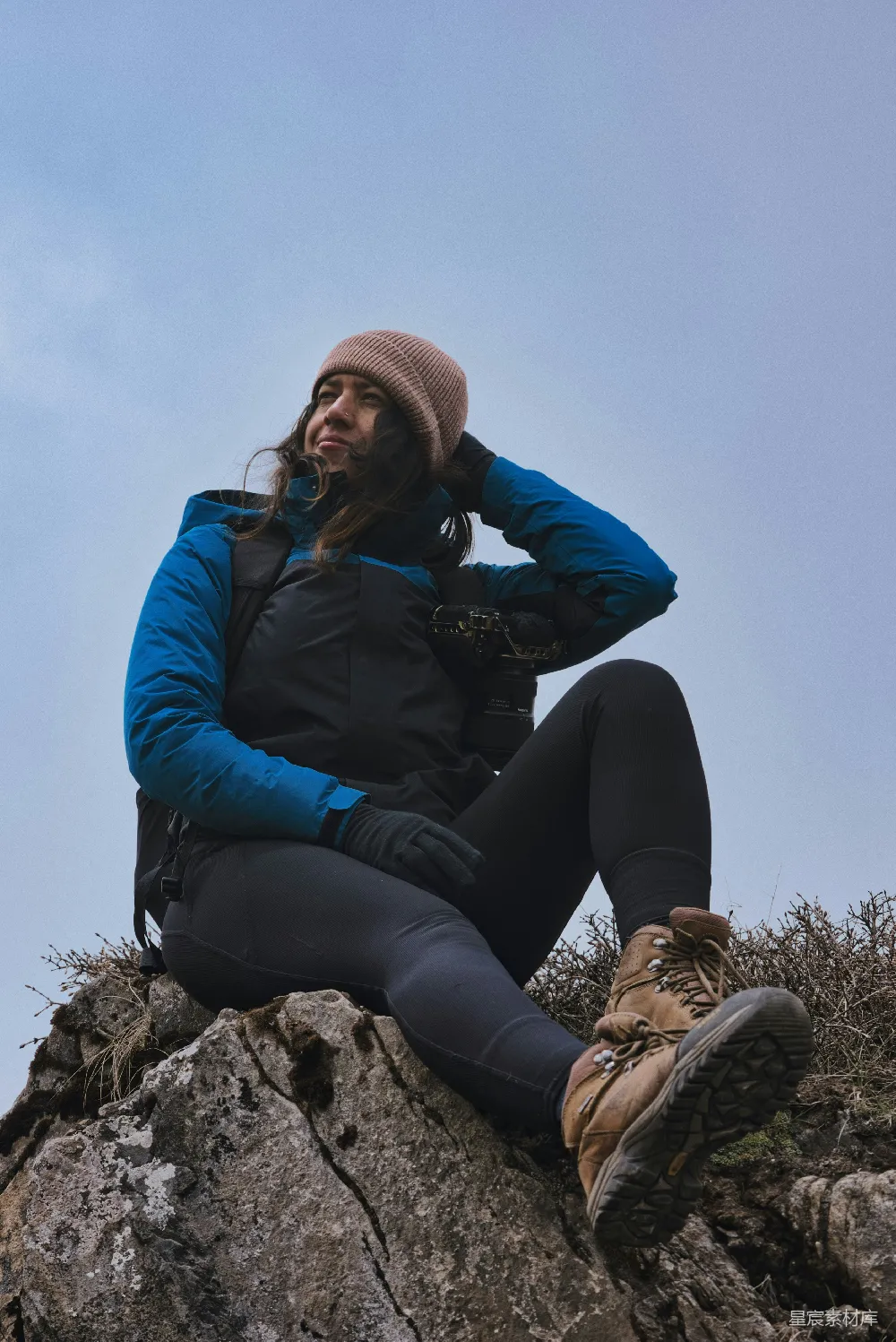 穿着徒步装备的女人坐在一块岩石突出处
