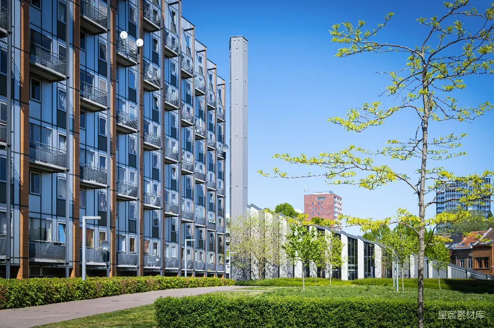 现代公寓建筑，带有绿色庭院和蓝天。