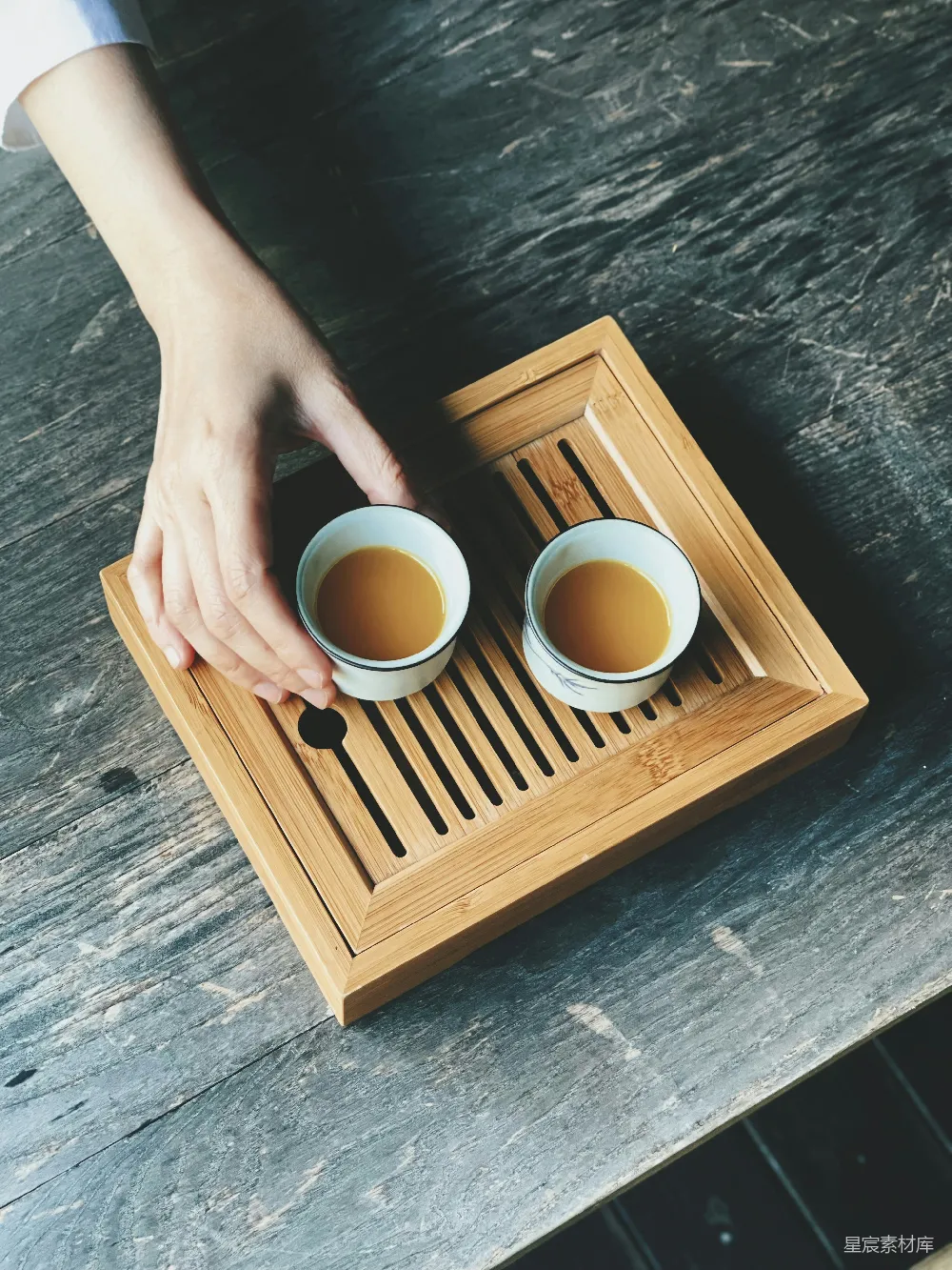一个拿着两个咖啡杯的托盘的人